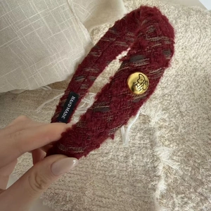 Detail of red tweed hair clip showing handmade label and gold buckle accent