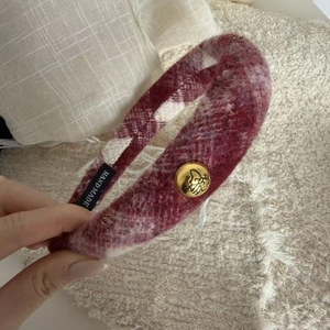 Close-up of red and white plaid headband with a golden bow button and handmade label