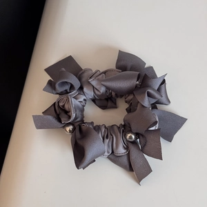 Vue détaillée du chouchou en satin gris foncé avec nœuds et perles métalliques argent