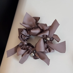 Détail du chouchou en satin rose poudré avec perle grise et centre de table en cristal