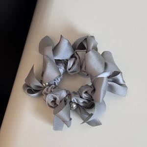 Vue détaillée du chouchou en satin gris argenté avec des perles élégantes et noeud