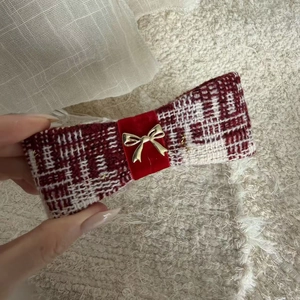 Close-up of red and white tweed banana hair clip with velvet ribbon and gold bow charm