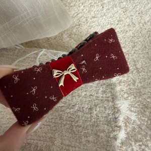 Detail of burgundy flocked hair clip with silver bows and gold metal accent