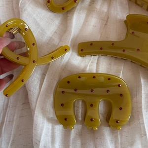 Detailed view of olive green hair claws with red polka dots on linen fabric background