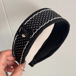 Close-up of black and white polka dot lace hair claw with bow detail and wavy trim