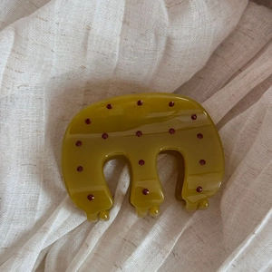 Detail view of olive green hair claw clip with vintage dark red polka dots on linen