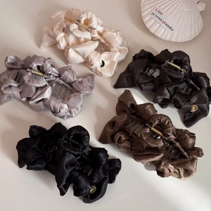 Detail of satin bow hair claws in various colors with elegant golden metal brand tags