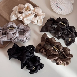 Elegant pleated satin bow hair claw clips in five neutral colors on a desktop