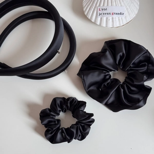 Dettaglio del set di elastici e cerchietti in raso nero con consistenza morbida e setosa