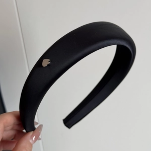 Dettaglio ravvicinato dell'elastico in raso nero con un piccolo ciondolo a cuore argento