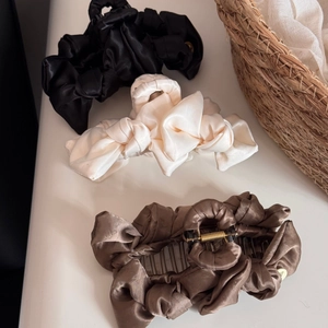 Detailed view of elegant satin bow hair claws in black, cream and coffee brown colors