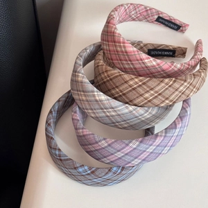Detailed view of handmade plaid fabric headbands showing textures and woven labels