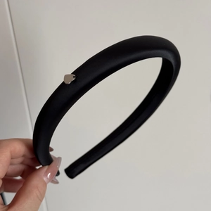 Dettaglio dell'elegante cerchietto in raso nero con un raffinato ciondolo a cuore argento