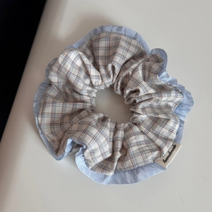 Detail eines karierten Haargummis mit blauem Satinrand und gewebtem Handmade-Label
