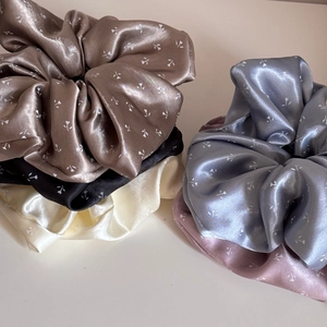 Gros plan de cinq grands chouchous en satin à fleurs de couleurs marron noir blanc et rose