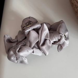 Detail view of large silver satin hair claw clip with elegant ruffled fabric pleats