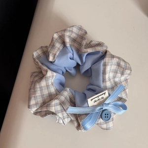 Detailansicht von blauem Karo-Haargummi mit Handmade-Etikett und Knopf-Dekor