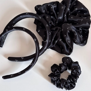Détail d'un ensemble cheveux en satin noir à motifs floraux avec serre-tête et chouchous