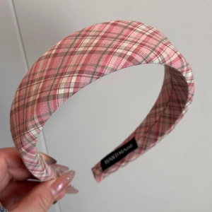 Detailed close-up of a wide pink plaid headband featuring a handmade inner label