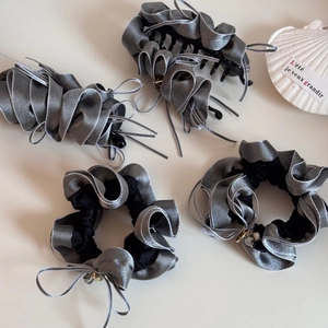Detail of grey satin hair accessories set with ruffled scrunchies and shark clips