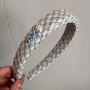 Detail eines blau karierten Haarreifens mit weißer Perle und handgefertigtem Schleifenanhänger