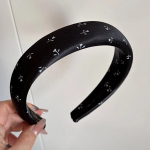 Détail d'un serre-tête rembourré en satin noir avec motif floral et doublure antidérapante
