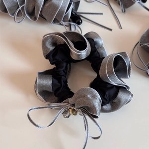Detail of grey satin scrunchie with bow, golden charm and sparkling clear bead