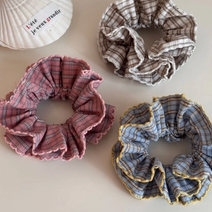 Detailed view of plaid scrunchies in pink, blue and beige with delicate crochet lace edges