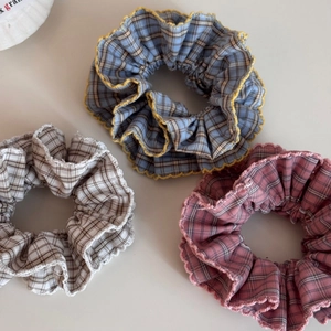 Detailed view of three plaid scrunchies in pastel blue, pink, and beige with lace edges