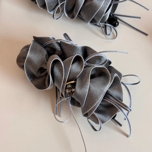 Close-up of elegant grey pleated satin hair tie with ribbon and crystal accents