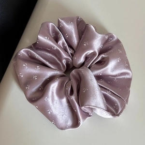 Détail d'un chouchou en satin rose poudré avec imprimé floral et texture lisse soyeuse