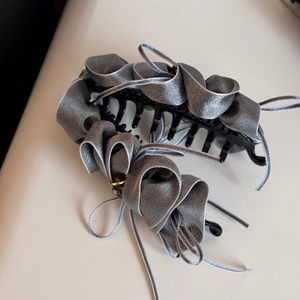 Close-up of grey satin ribbon hair claw clip featuring elegant layered ruffles and ties