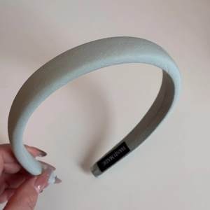 Detail of mint green padded sponge headband featuring a handmade label on the inner side