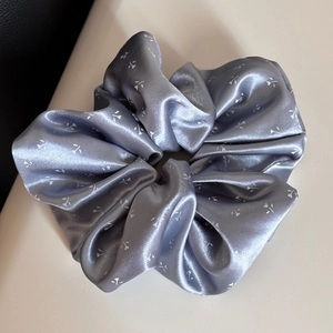 Vue détaillée du chouchou en satin fleuri gris-violet avec plis doux et éclat élégant