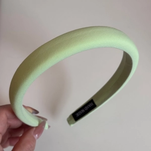 Detail of mint green padded satin headband with handmade label inside for women