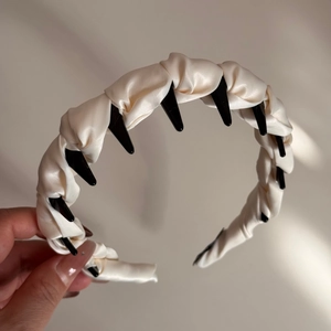 Détail d'un serre-tête en satin crème avec dents noires antidérapantes et plis