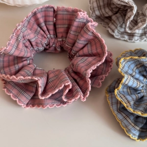 Detail of checkered fabric scrunchies in pink, blue and beige with scalloped lace trim