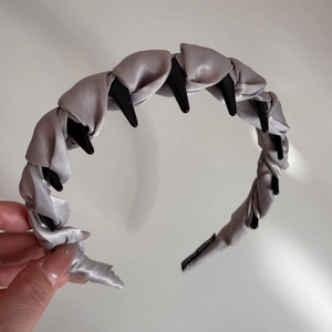 Détail du serre-tête en satin gris argenté montrant les dents antidérapantes et l'étiquette