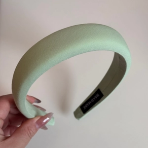 Detail shot of mint green padded sponge headband with handmade label and soft fabric texture