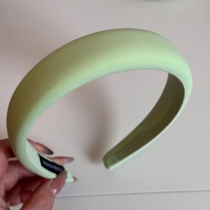 Detail of light green padded sponge headband featuring a handmade woven fabric label