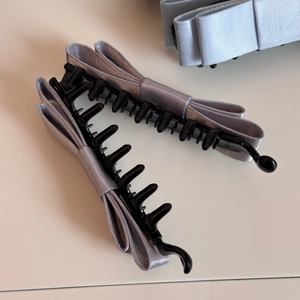 Detail of silver-grey satin bow banana clip showing smooth texture and inner plastic teeth