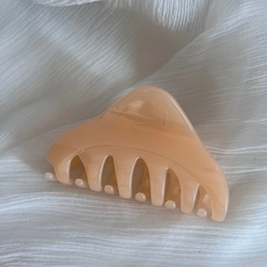 Détail de la pince à cheveux brillante couleur crème sur fond de tissu de soie blanche