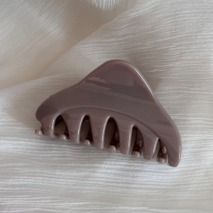 Détail de la pince à cheveux mauve élégante sur fond de tissu blanc texturé de qualité