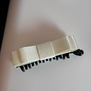 Detail of elegant cream satin bow banana hair clip with secure black plastic teeth