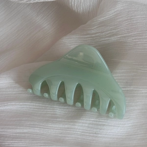 Gros plan d'une pince à cheveux vert menthe sur fond de tissu blanc doux