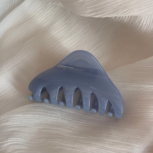 Détail d'une pince à cheveux triangulaire en résine bleu clair sur mousseline beige