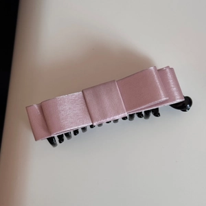 Detailed macro view of the multi-layered pink satin bow and black banana hair clip structure