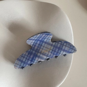 Detail of blue and white checkered hair claw clip with wavy edges on a ceramic dish