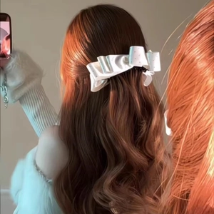 White satin bow hair clip with polka dots shown on back of dark wavy hair