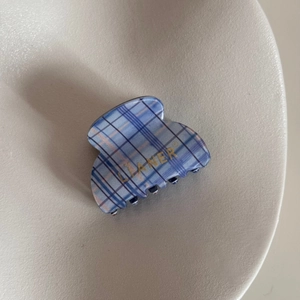 Detailed top view of blue and white plaid claw clip with gold brand logo